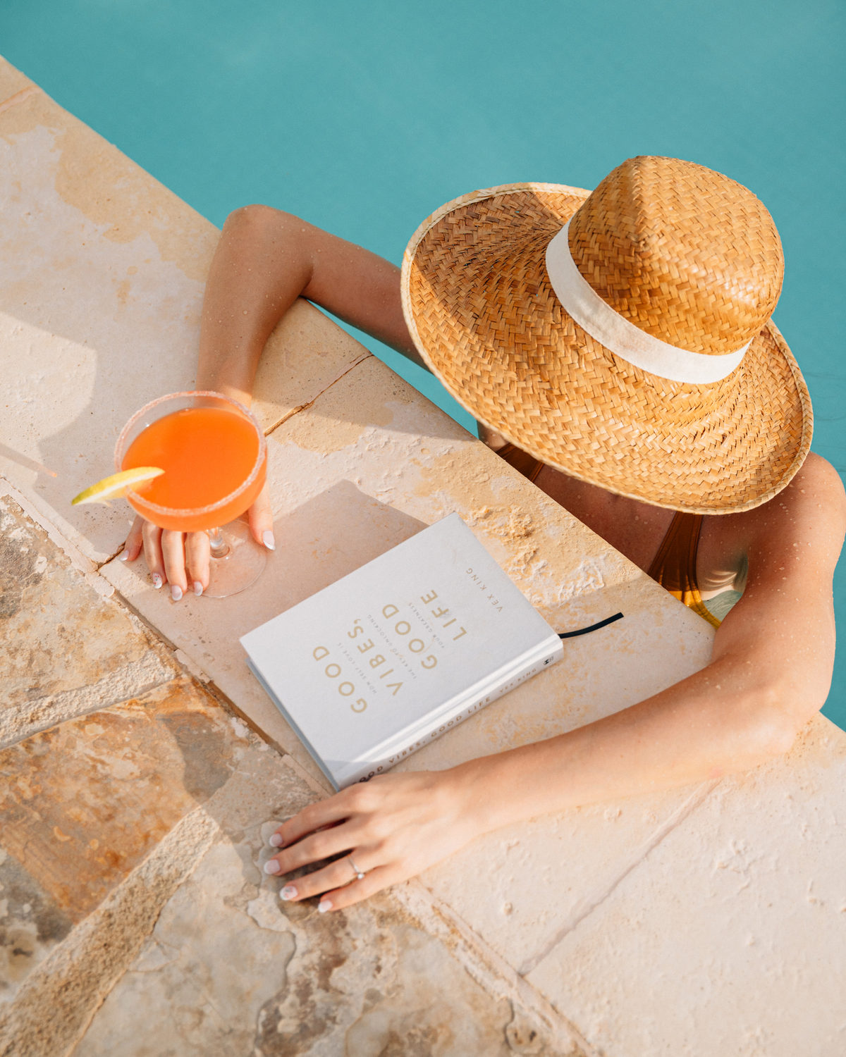 Journal, straw hat and a fresh juice on a terrace table