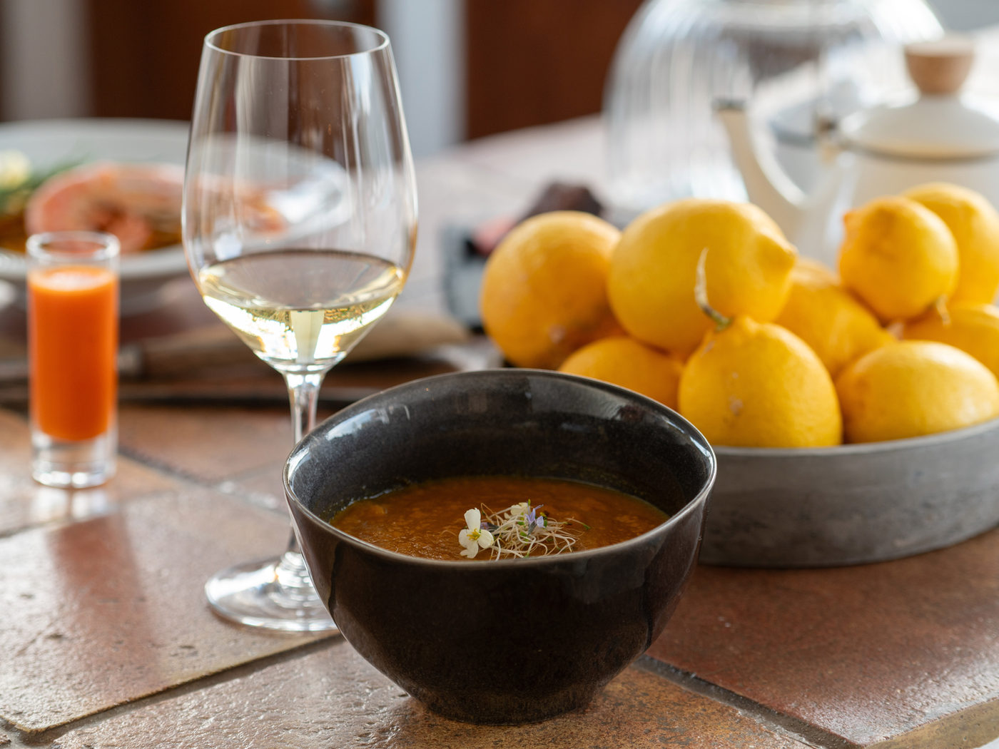 A bowl of soup, juice and lemons on a table at the finca