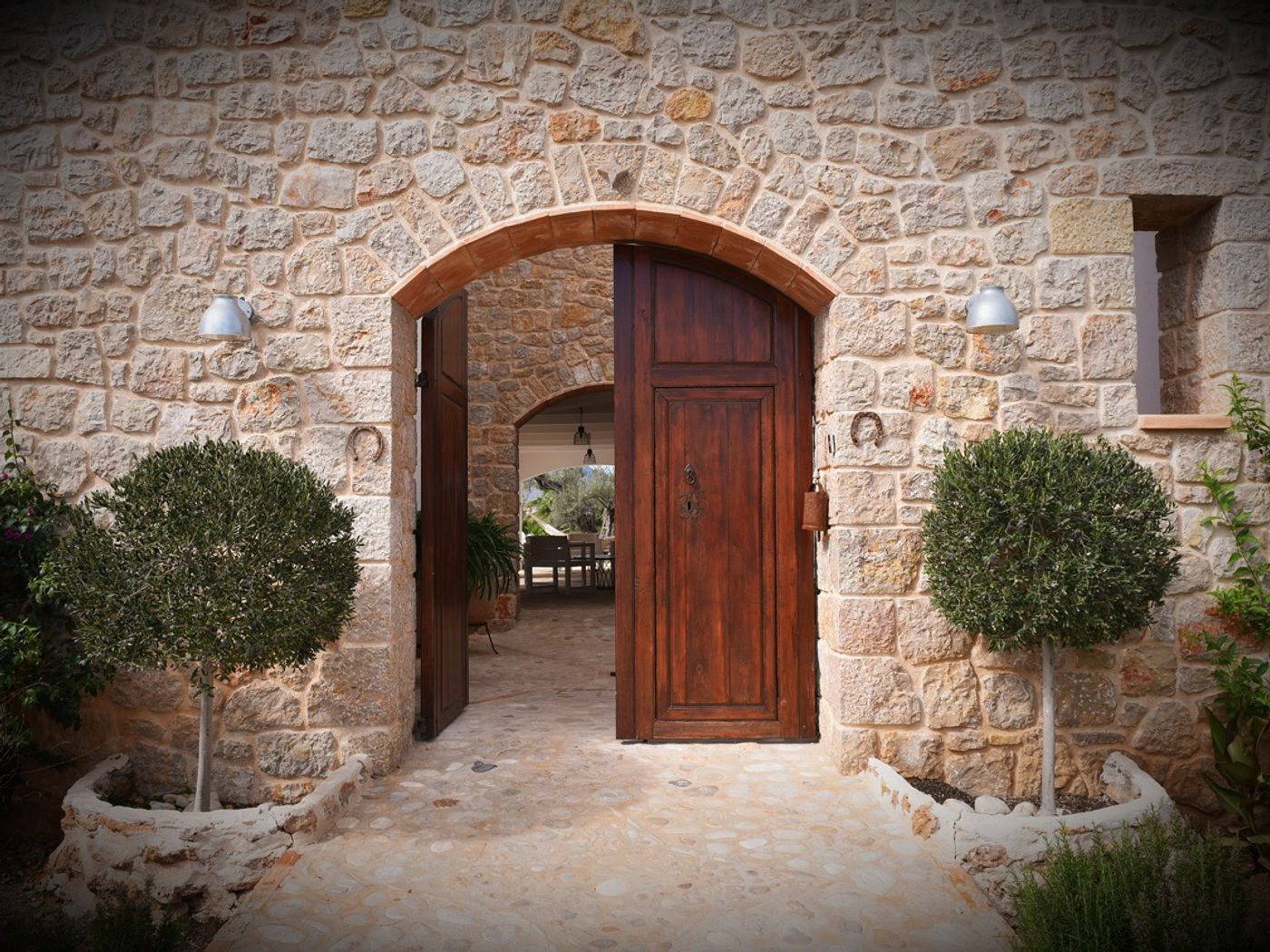 Sunlit stone courtyard at Cuatre Finques with linen drapes and olive branches